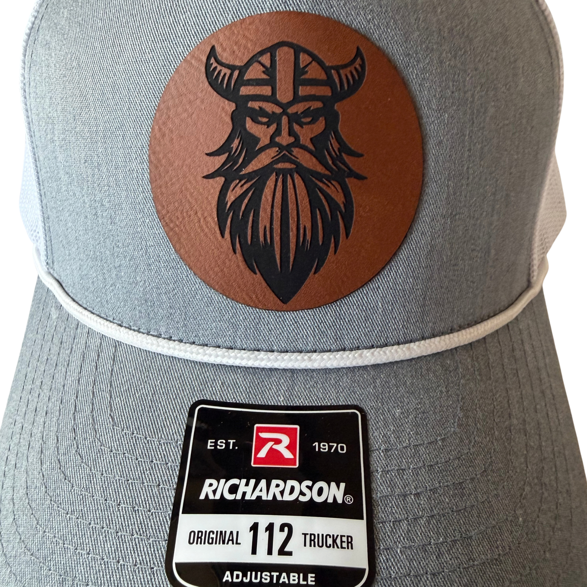 Close-up of the brown Veien Viking leather patch and white rope on the heather grey cap.